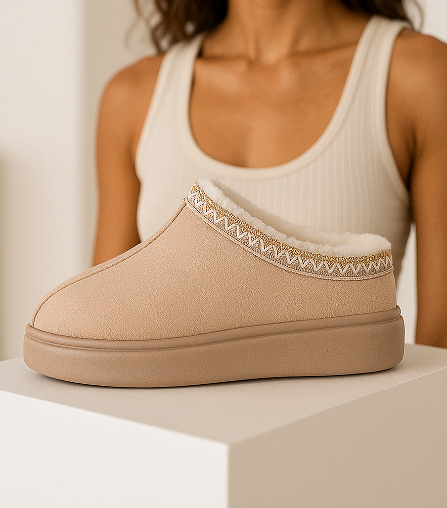 Beige slipper with decorative trim on a neutral background