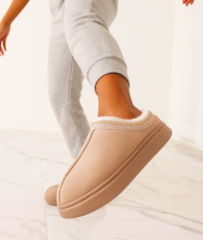 Beige slipper worn by a person on a light background