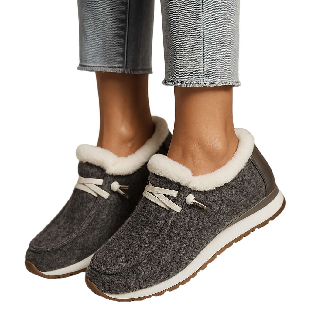 Gray slippers with white fur lining worn by a person in jeans.