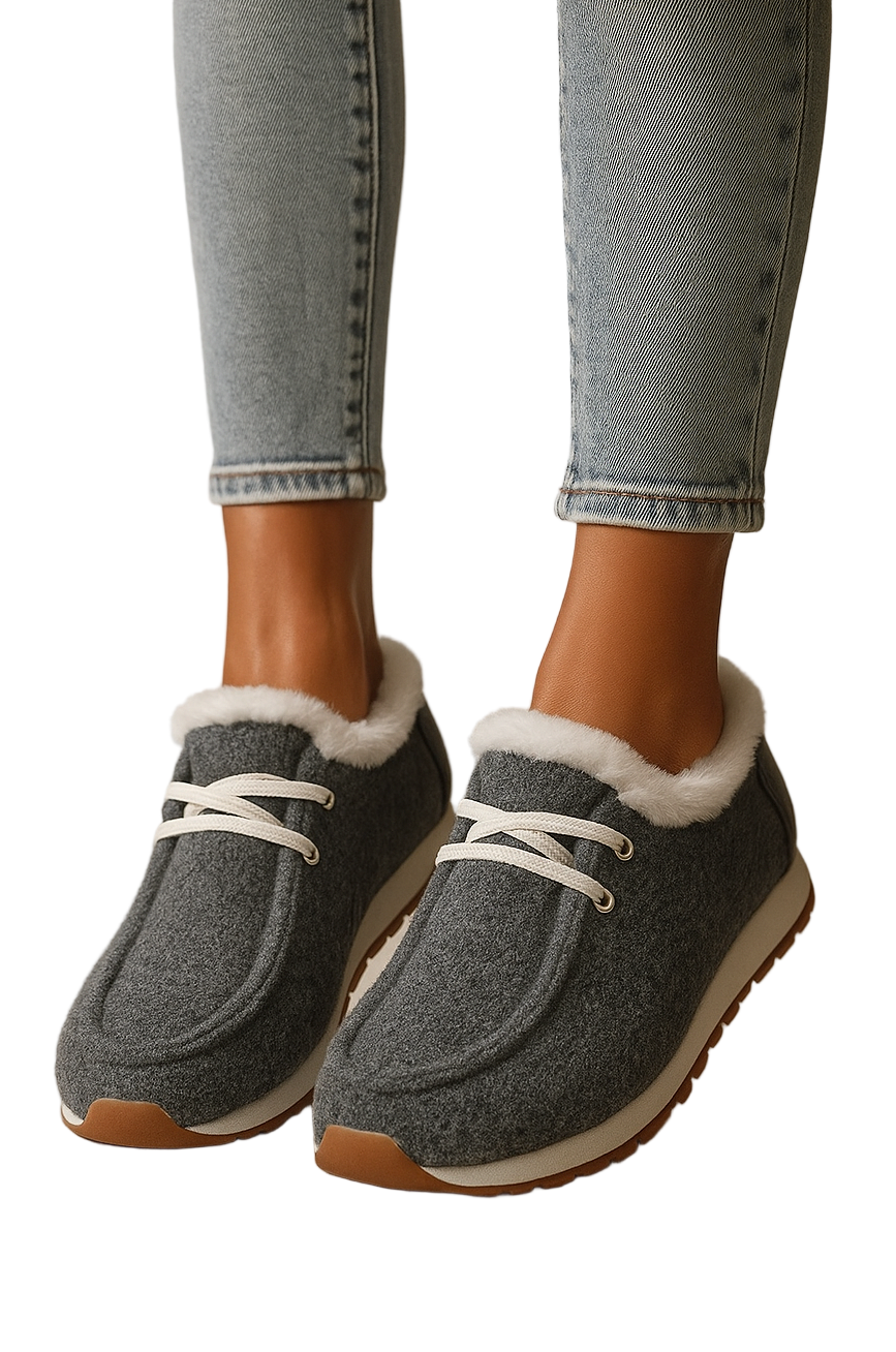Gray slippers with white fur lining worn with light blue jeans on a neutral background
