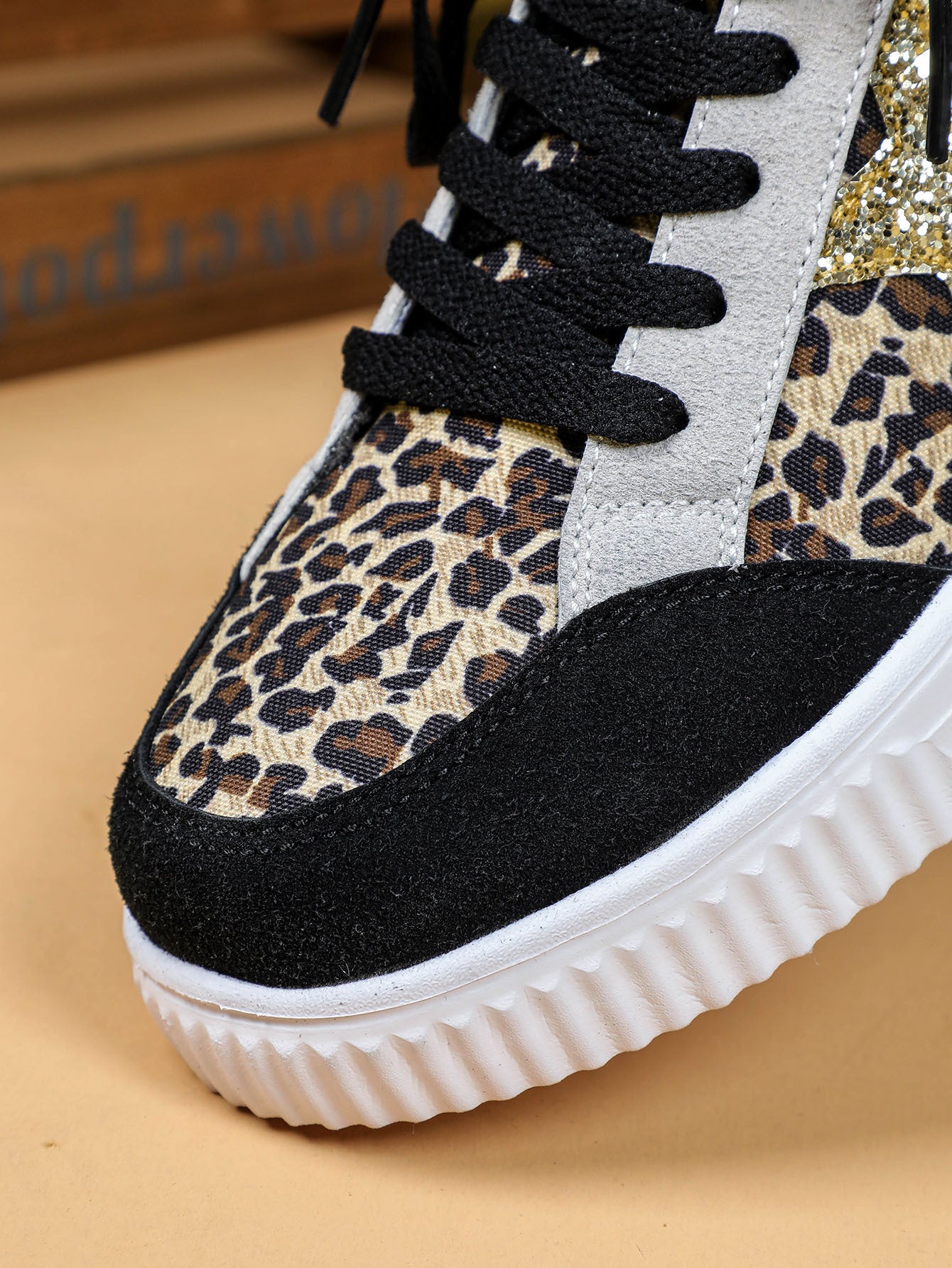Sneaker with leopard print pattern and black sole on a beige background