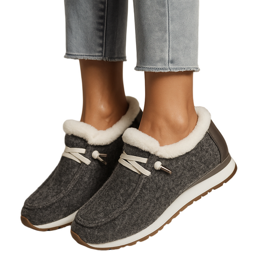 Gray slippers with white fur lining worn by a person in jeans.
